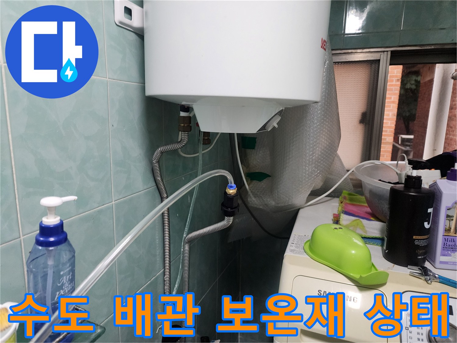 보온재로 덮인 은색 배관과 벽면 타일의 접합부 모습