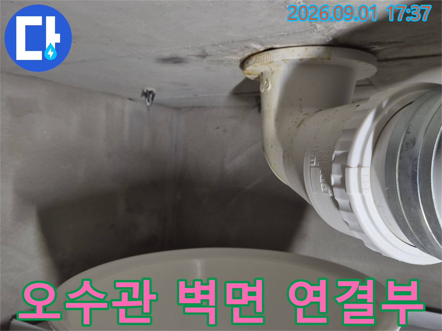 벽면에 연결된 오수관의 이음새와 배관 주변을 촬영한 사진입니다.