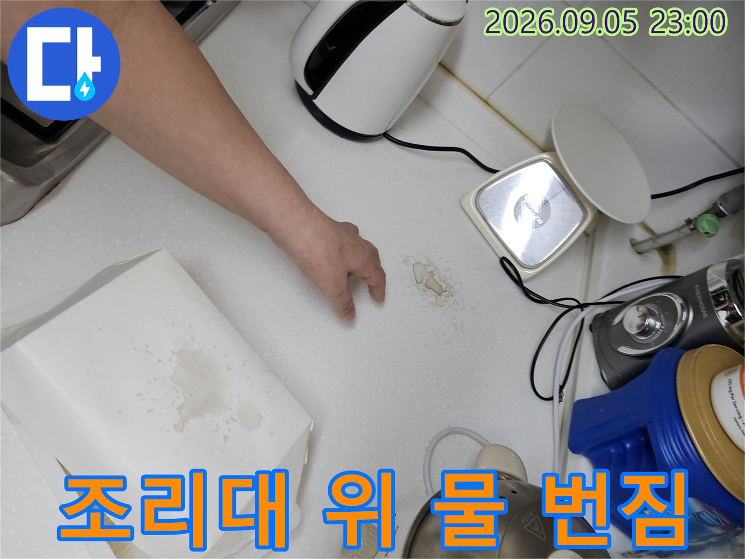 주방 조리대 상판에 넓게 퍼진 물 번짐과 건조된 자국을 점검 중