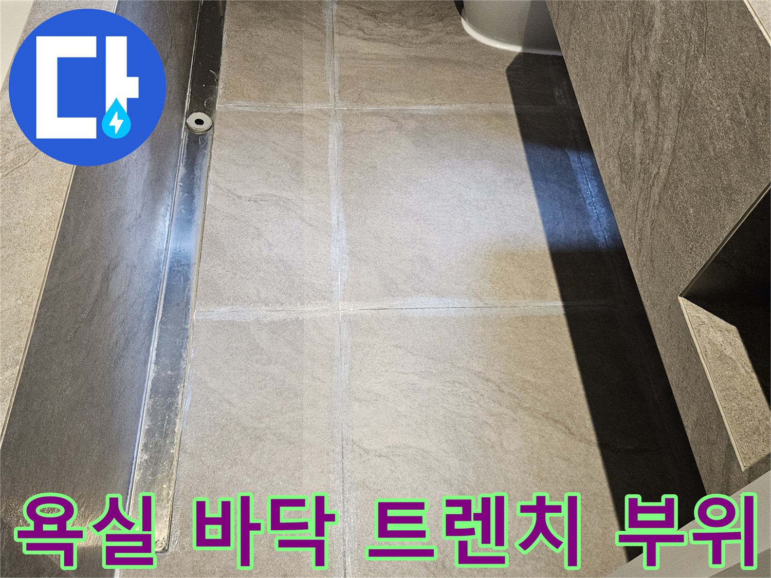 대리석 타일로 마감된 욕실의 배수 트렌치 주변 모습입니다.