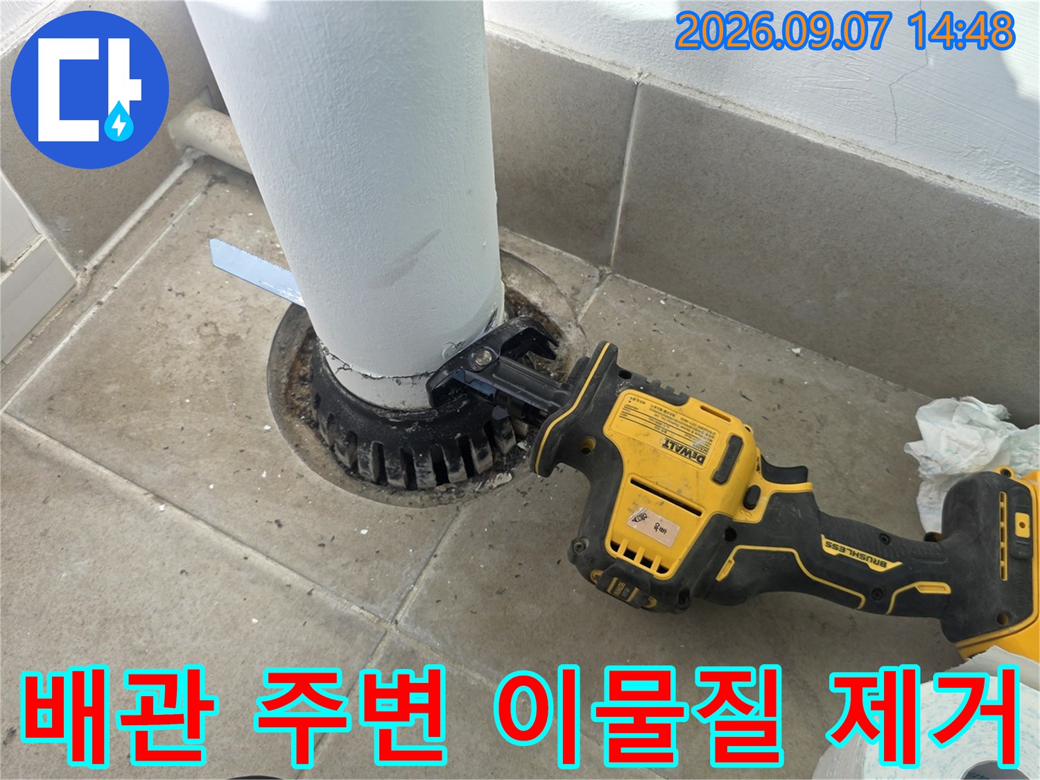 전동 드릴을 사용하여 우수관 하단부의 노후된 배관 부위를 정리하고 있습니다.