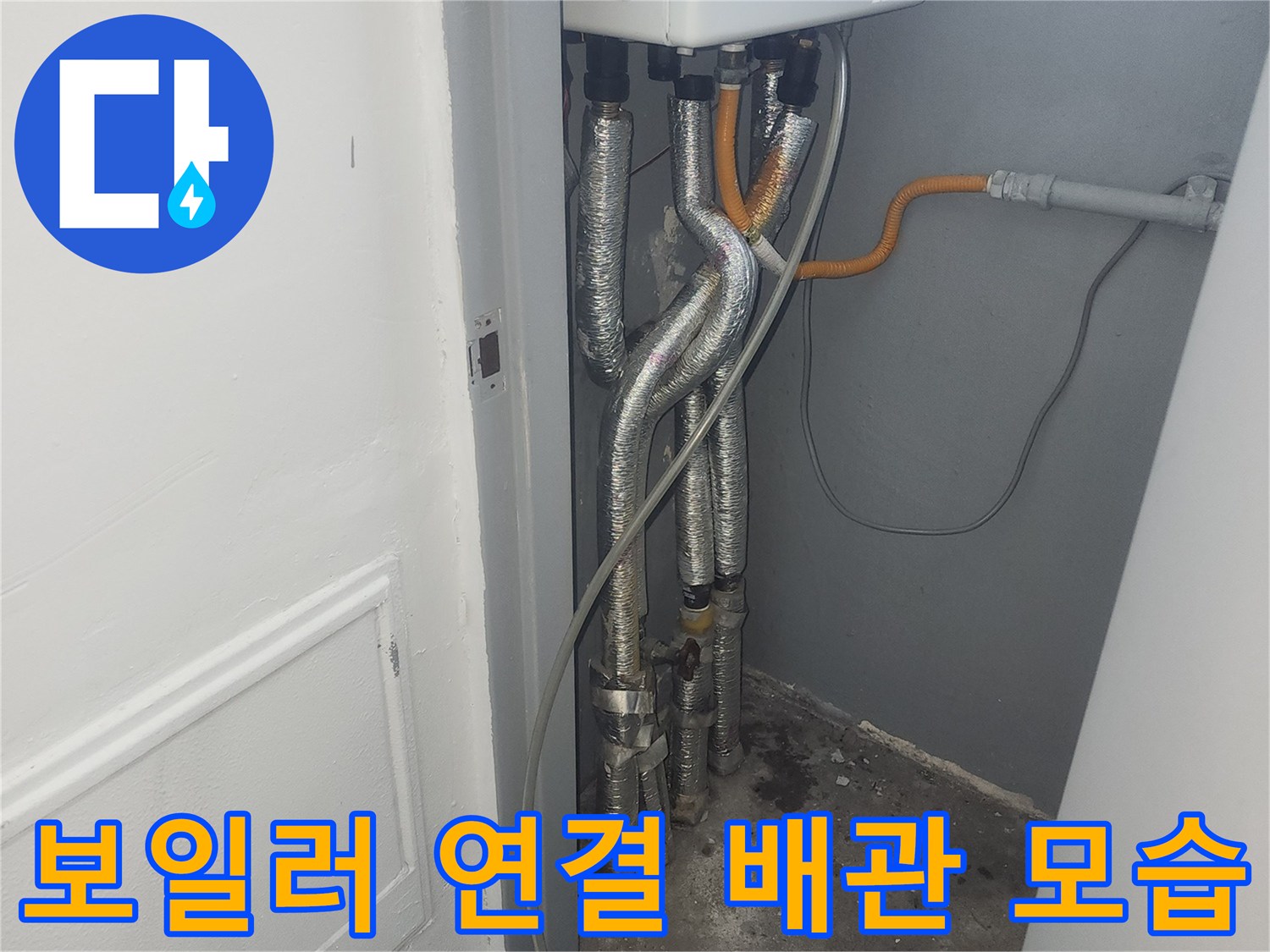 보일러 하단에 설치된 은색 주름관과 노란색 관의 연결 상태입니다.