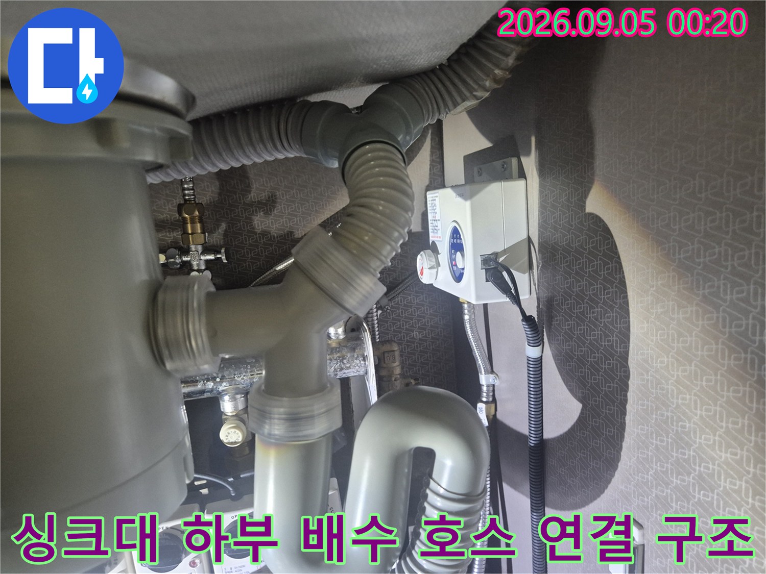 굴곡진 회색 주름관과 벽면 배수관의 연결 부위 모습
