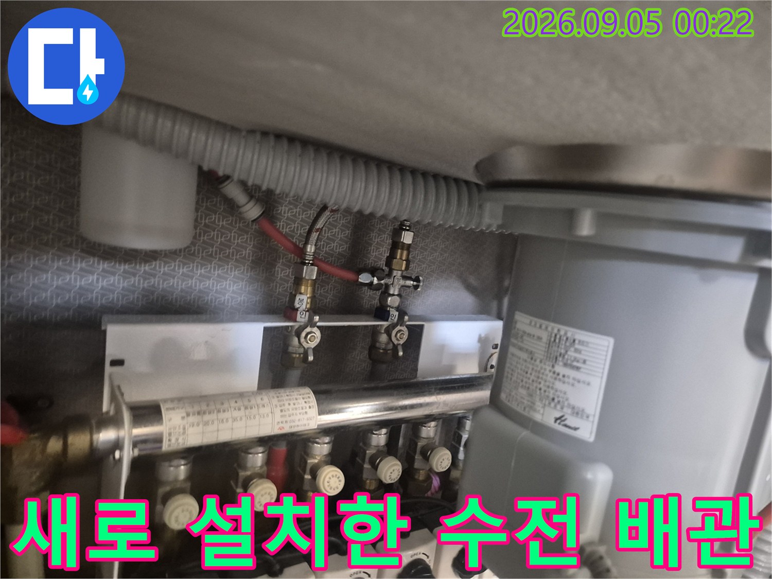 싱크대 하부장에 연결된 은색 배관과 밸브의 세밀한 점검 모습