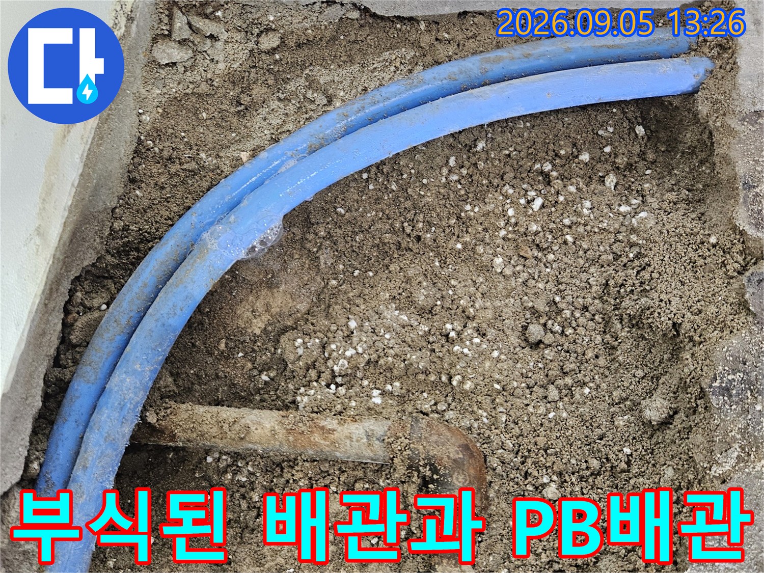벽면 흙 속에서 드러난 파란색 배관과 녹슨 금속 부속