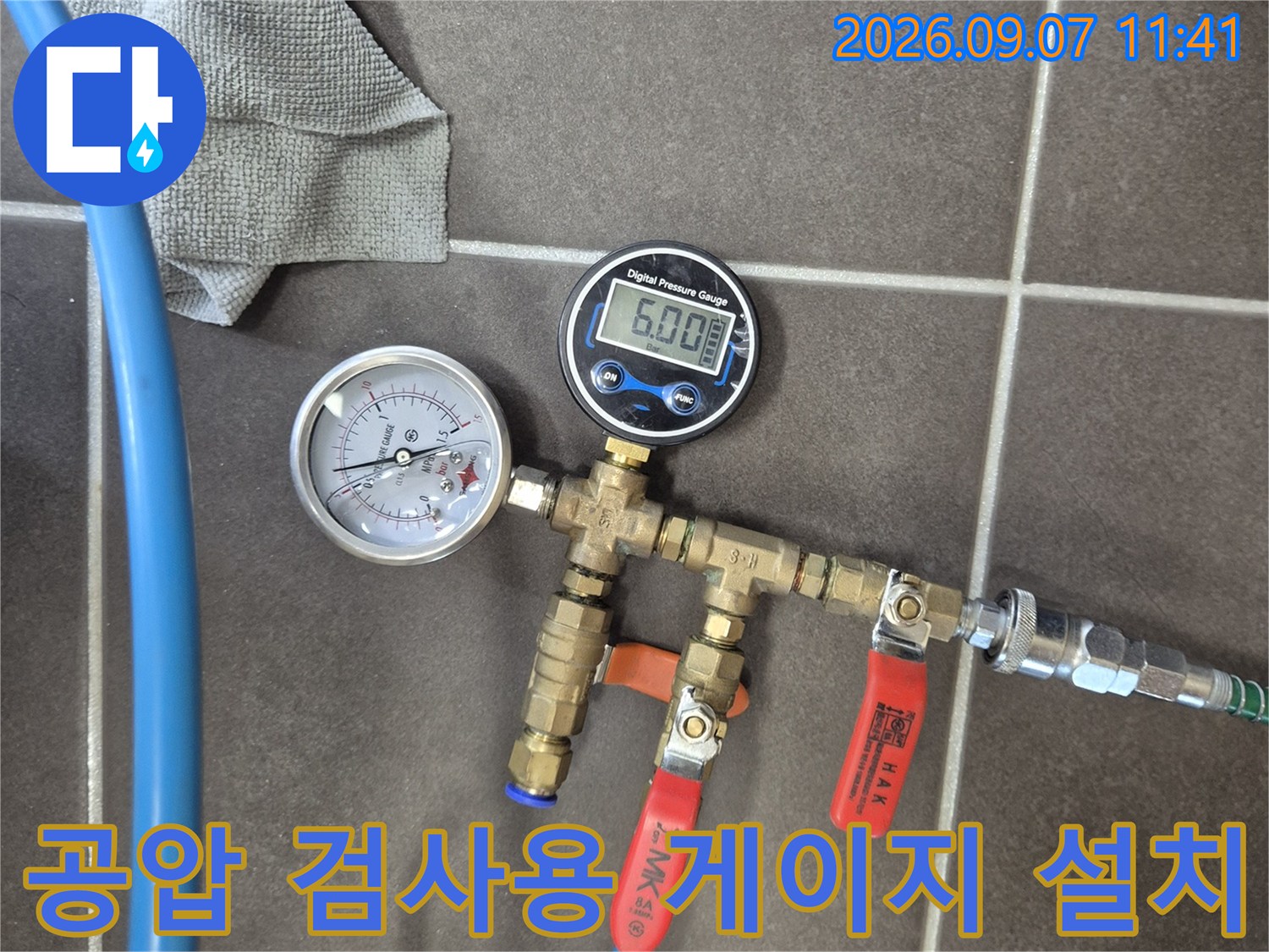 파란색 호스가 연결된-배관 장치와-숫자가 표시된-디지털 압력계의 모습