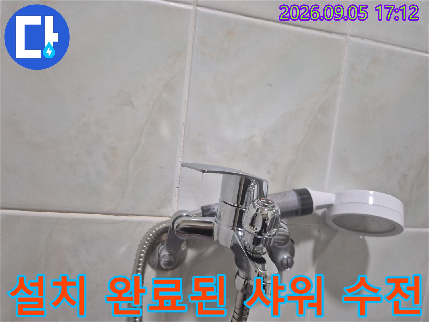 새하얀 타일 벽면 배경으로 설치된 은색 샤워기 수전 상세 사진입니다.