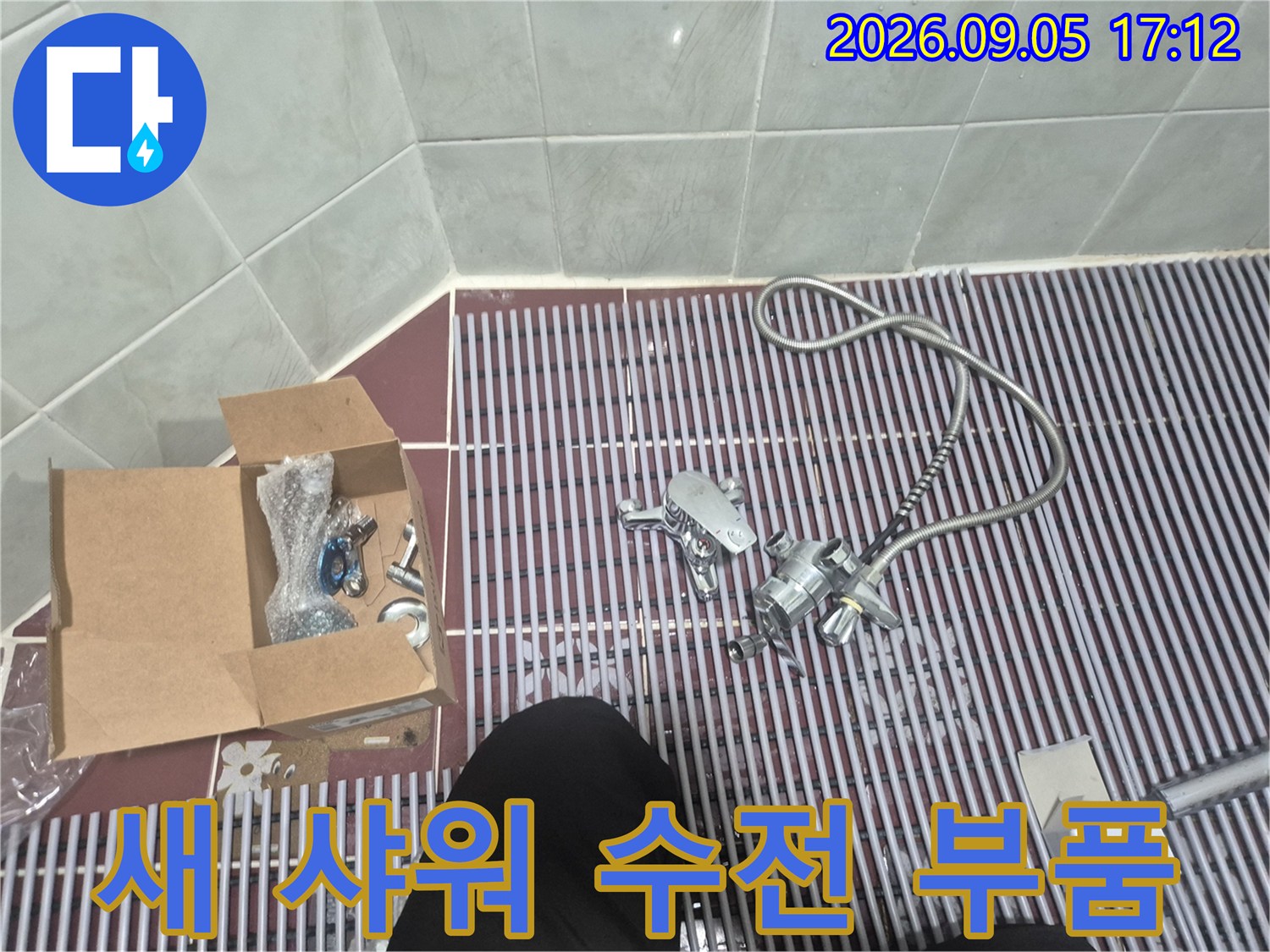 욕실 배수 트렌치 위에 놓인 샤워기 호스와 수전 본체