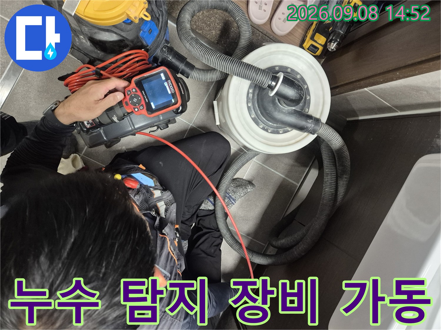 붉은 호스와 연결된 배관 검사 장비를 점검하는 모습입니다.