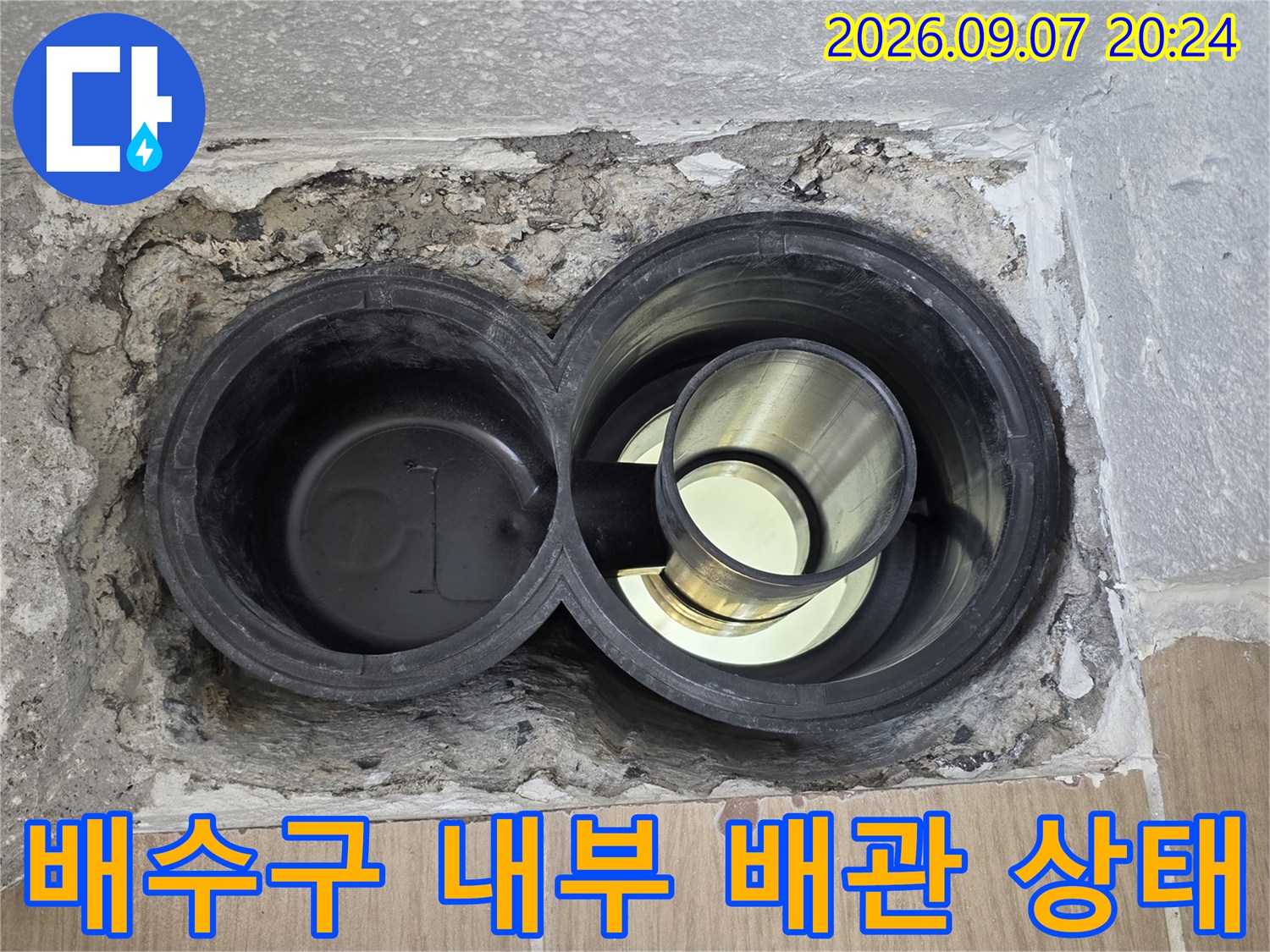 배수구 주변의 노출된 배관과 불량한 마감재를 나타내는 사진입니다.