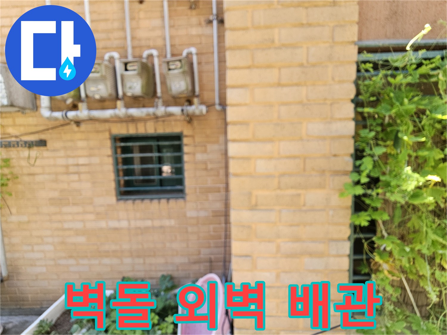 갈색 벽돌 외벽에 설치된 수도 계량기 및 수직 배관