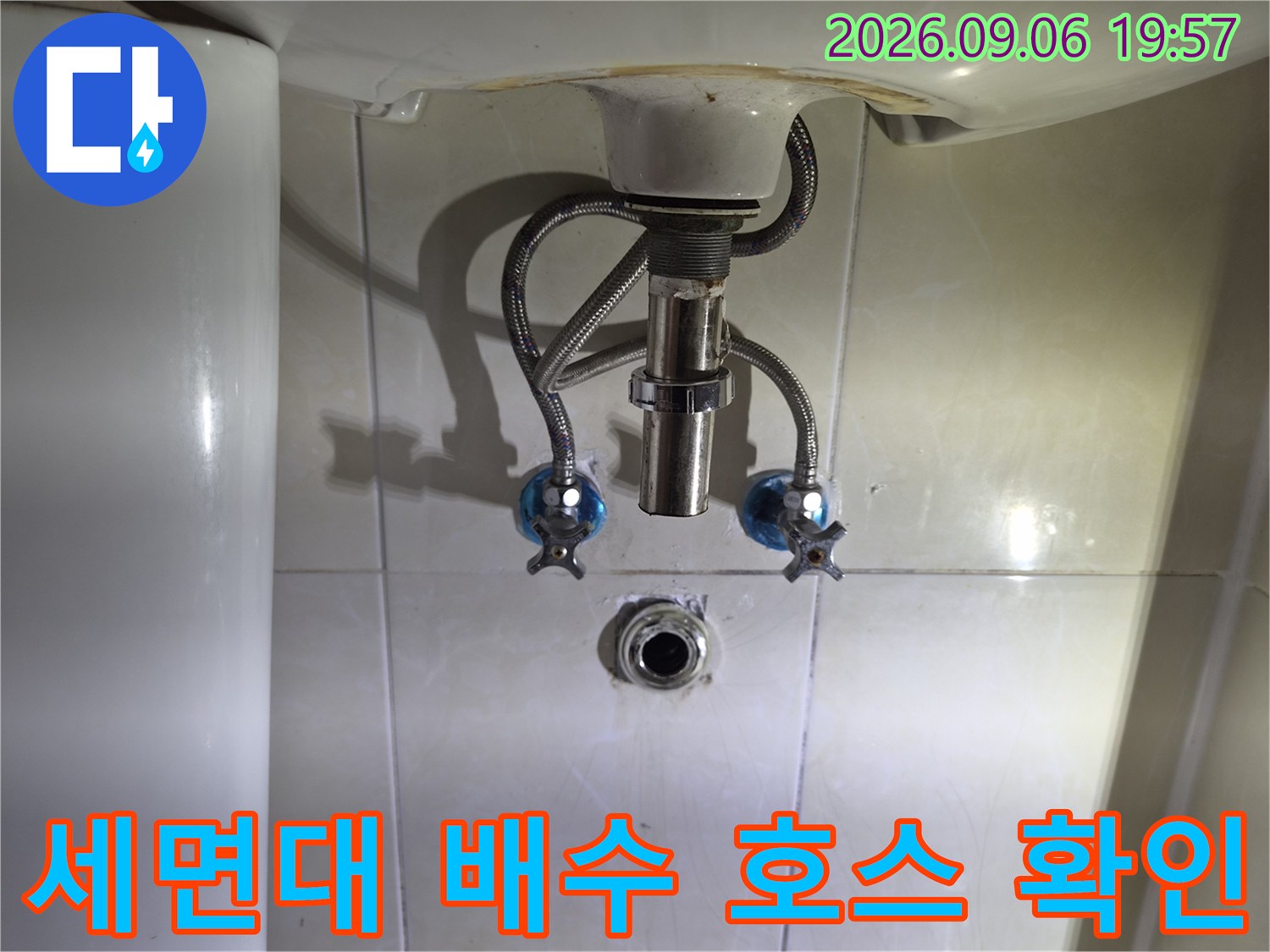 세면대 밑으로 연결된 은색 금속 호스와 밸브 모습