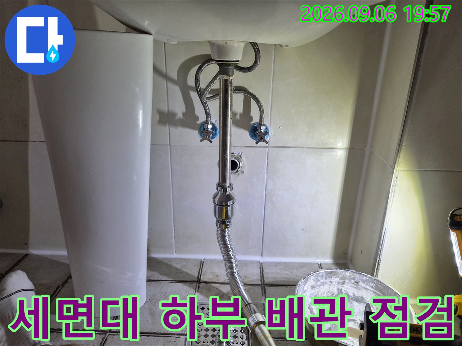 세면대 아래쪽의 파란색 수전 밸브와 은색 배수 호스 연결 부위