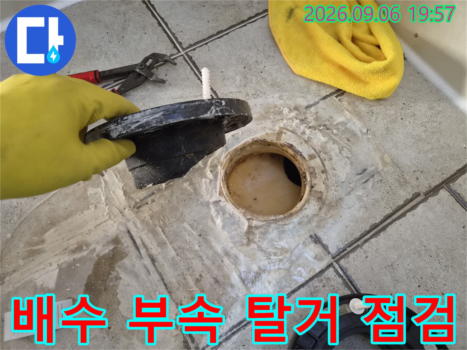 탈거된 배수 부속과 물기가 보이는 하수구 주변 타일