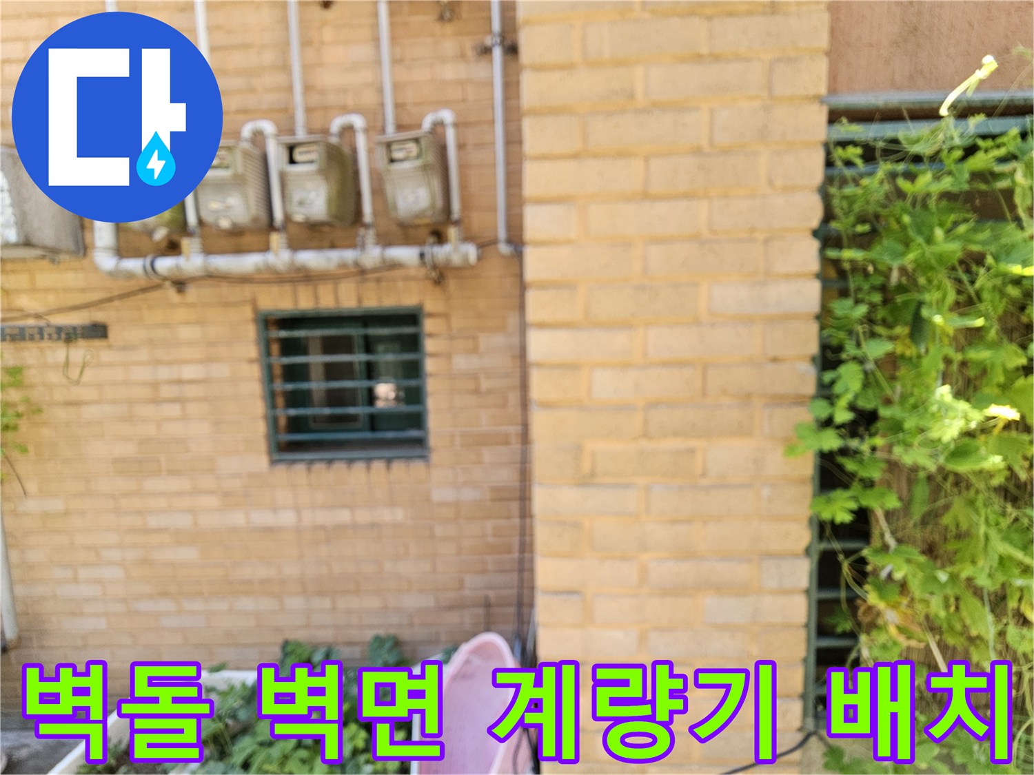 황색 벽돌 외벽에 일렬로 설치된 수도 계량기와 배관 연결 부위입니다.