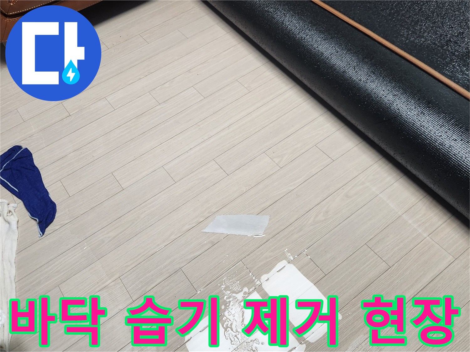 젖은 장판 아래 바닥을 닦아내는 작업 이미지입니다.