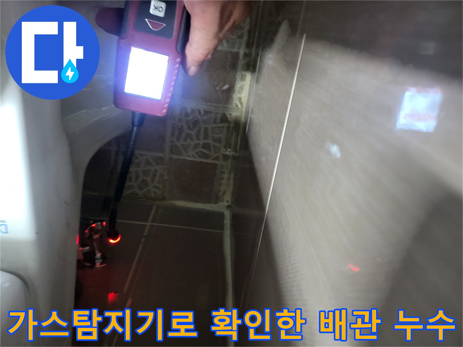 화장실 벽면 타일 틈 사이로 가스 탐지기를 넣어 배관 상태를 점검하는 모습입니다.