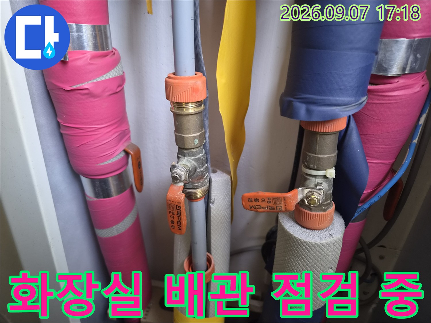 분홍색과 파란색으로 보온된 배관 및 금속 밸브의 누수 여부 확인 작업