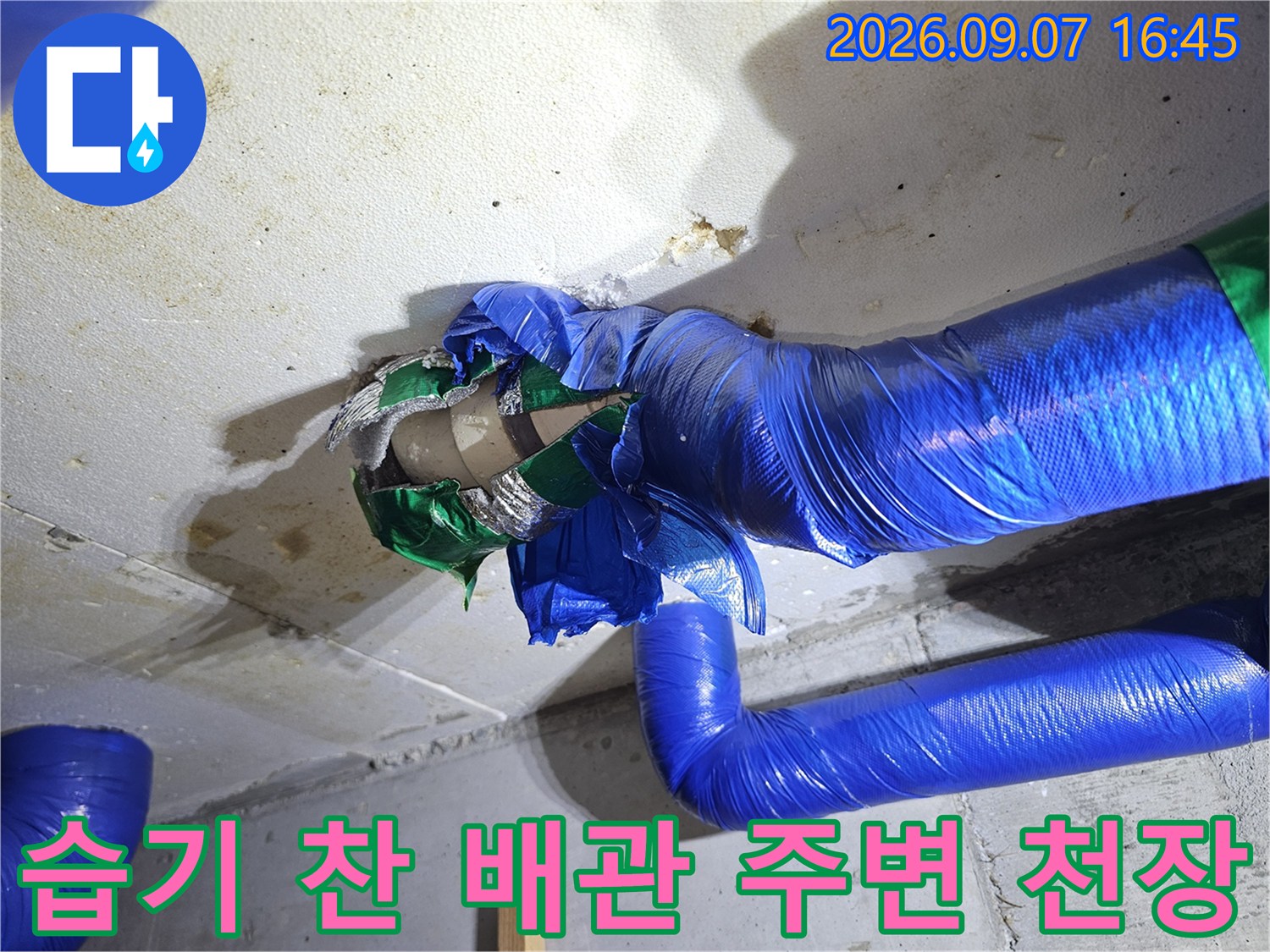 파란색 보온재로 감싸진 배관과 물에 젖은 콘크리트 면