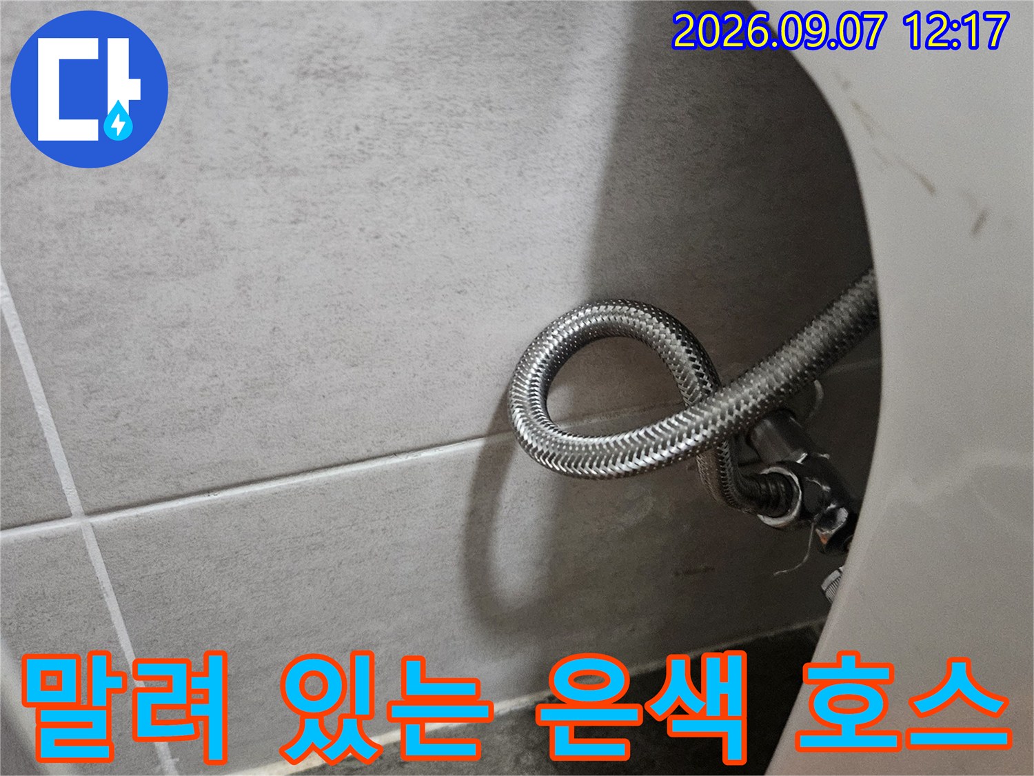 싱크대 밑부분에 위치한 둥글게 말린 스테인리스 배관 호스