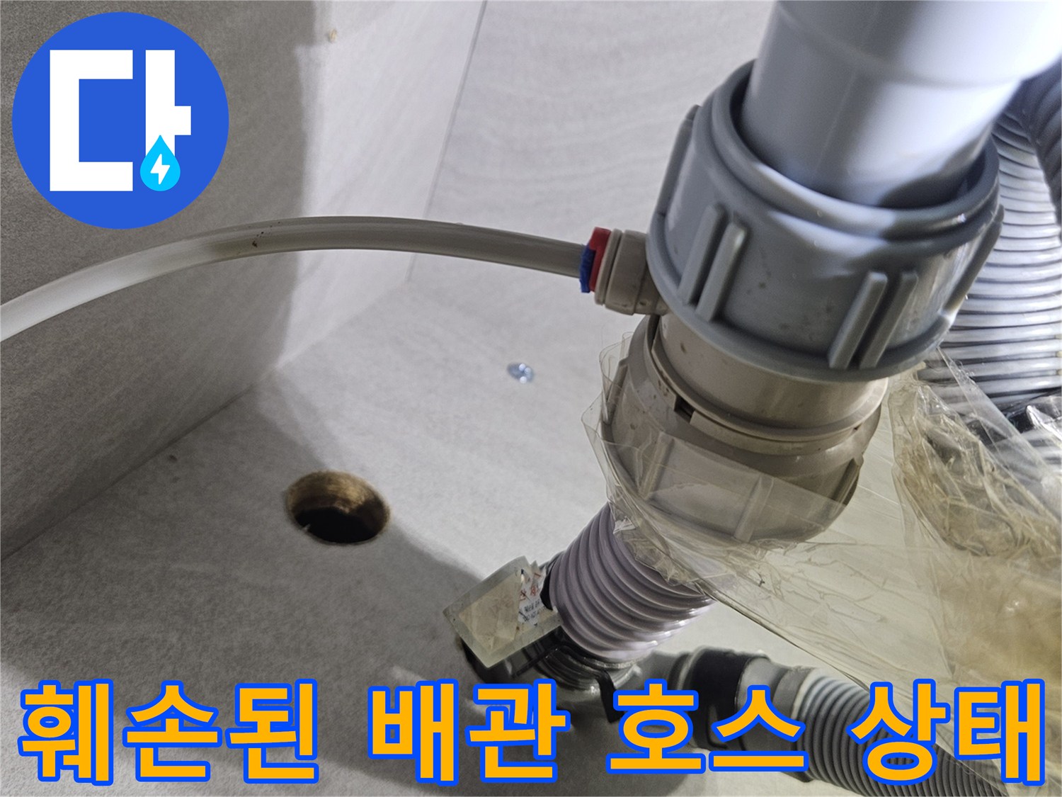 싱크대 하부의 훼손된 호스와 연결 부속의 근접 촬영 사진