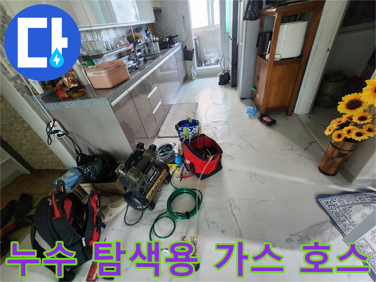 싱크대 밑 바닥에 놓인 붉은색 공구함과 가스 연결 호스