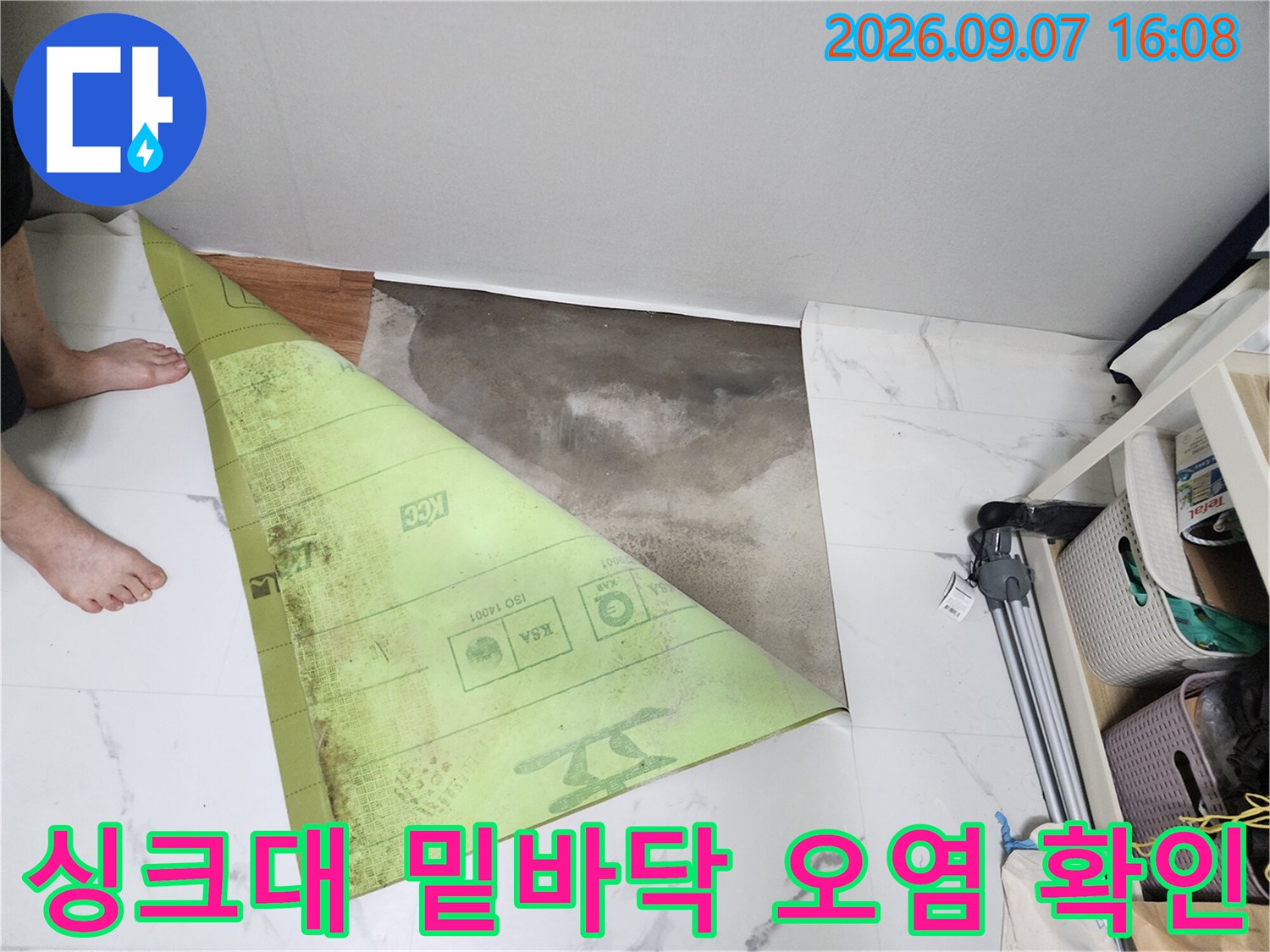 연천 전곡 현장 싱크대 아래쪽의 젖은 바닥 상태를 근접 촬영한 사진입니다.
