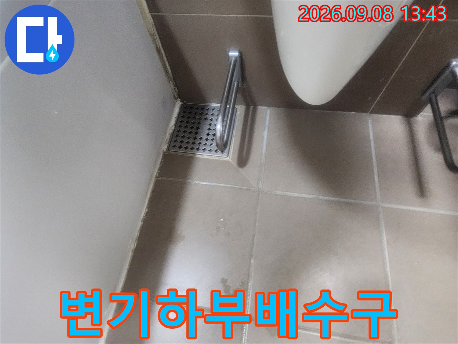 변기 하단부에 위치한 배수구와 타일 경계면을 촬영한 사진입니다.