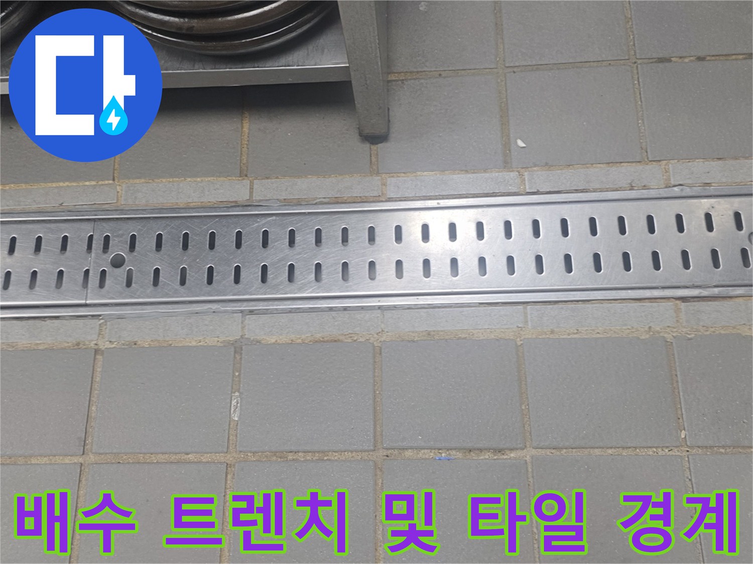 금속 재질의 배수구 트렌치와 인접한 회색 타일 바닥의 모습