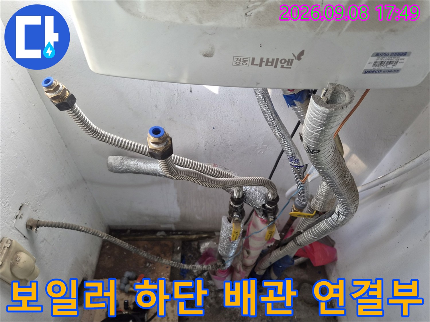 보일러 본체 아래쪽으로 뻗어 나온 은색 보온재 배관들의 모습입니다.