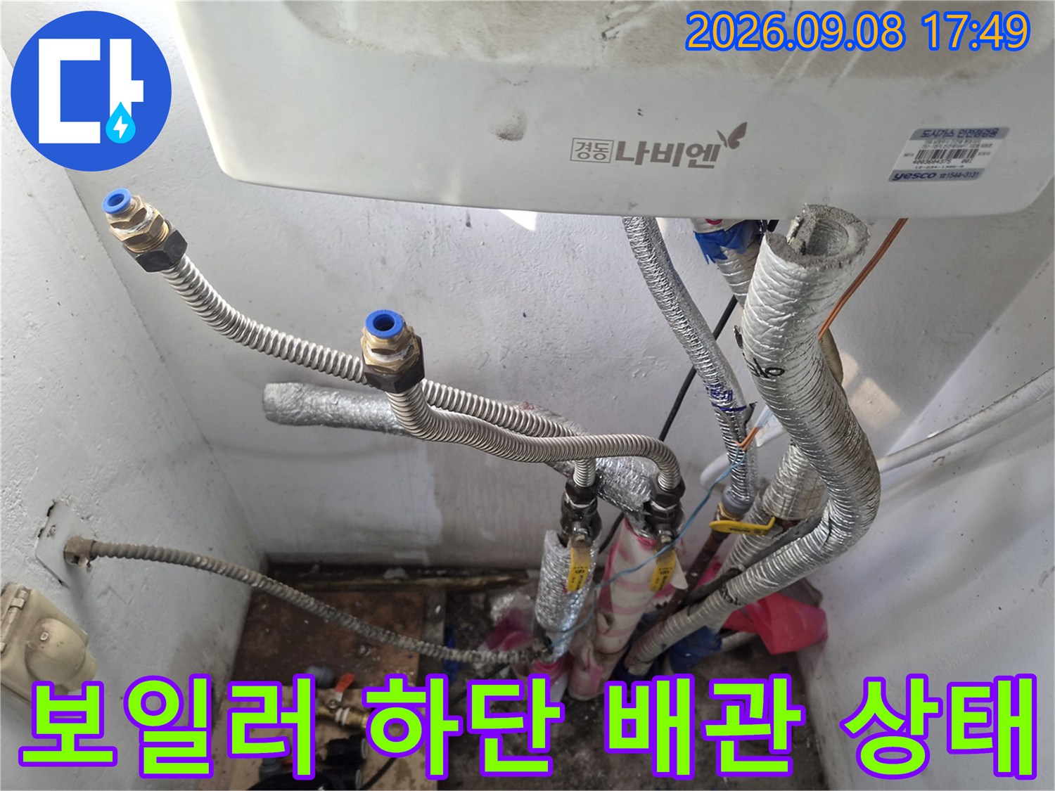 보일러 아래쪽의 은색 보온재로 감싸진 배관들-연결 부위 점검 중