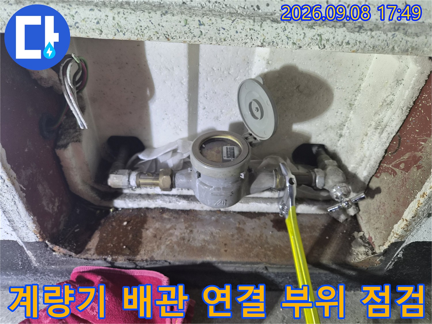 수도 계량기와 금속제 밸브가 설치된 배관 내부의 모습입니다.