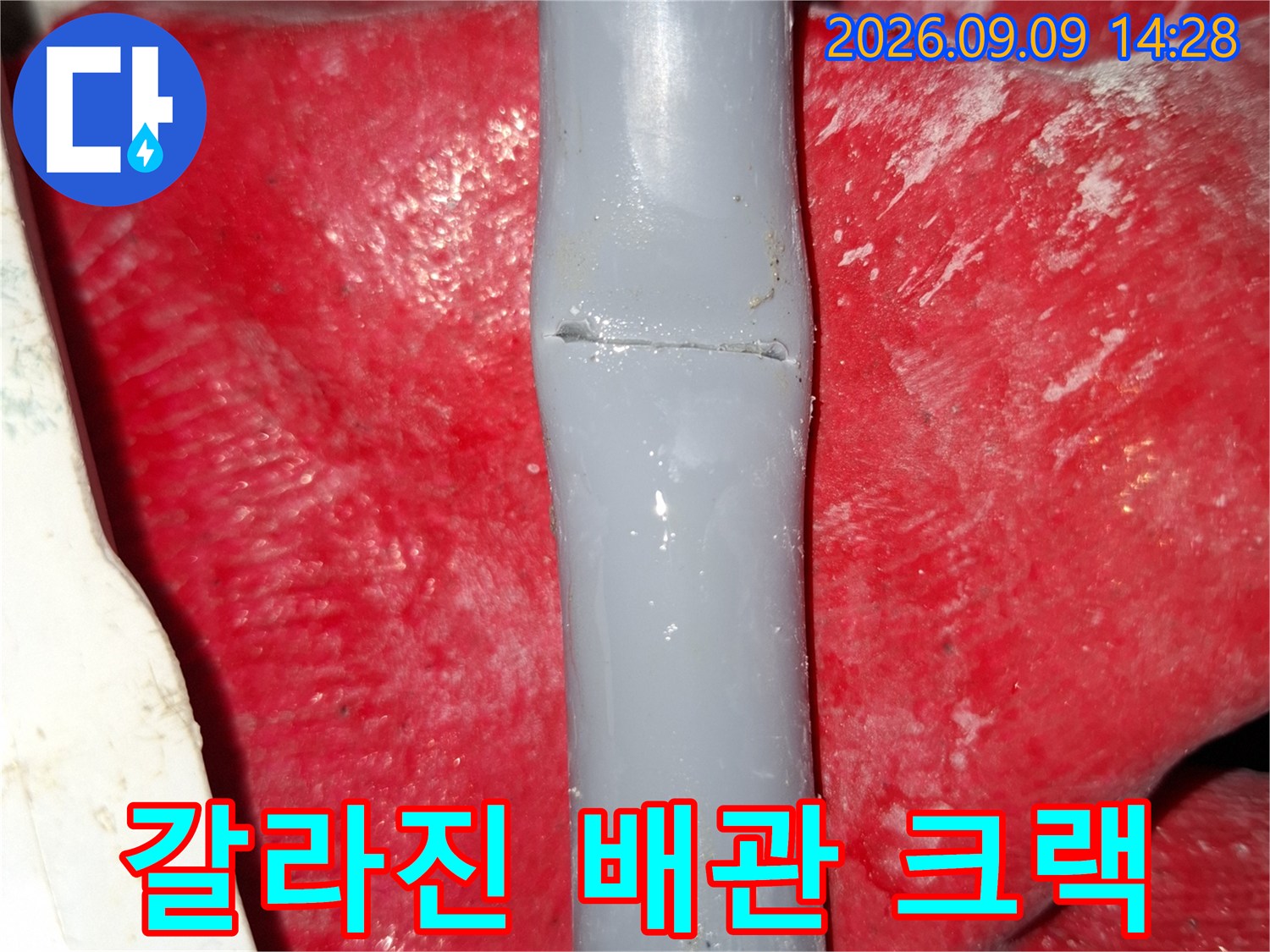 회색 배관 중간에 발생한 갈라진 틈을 찍은 사진입니다.