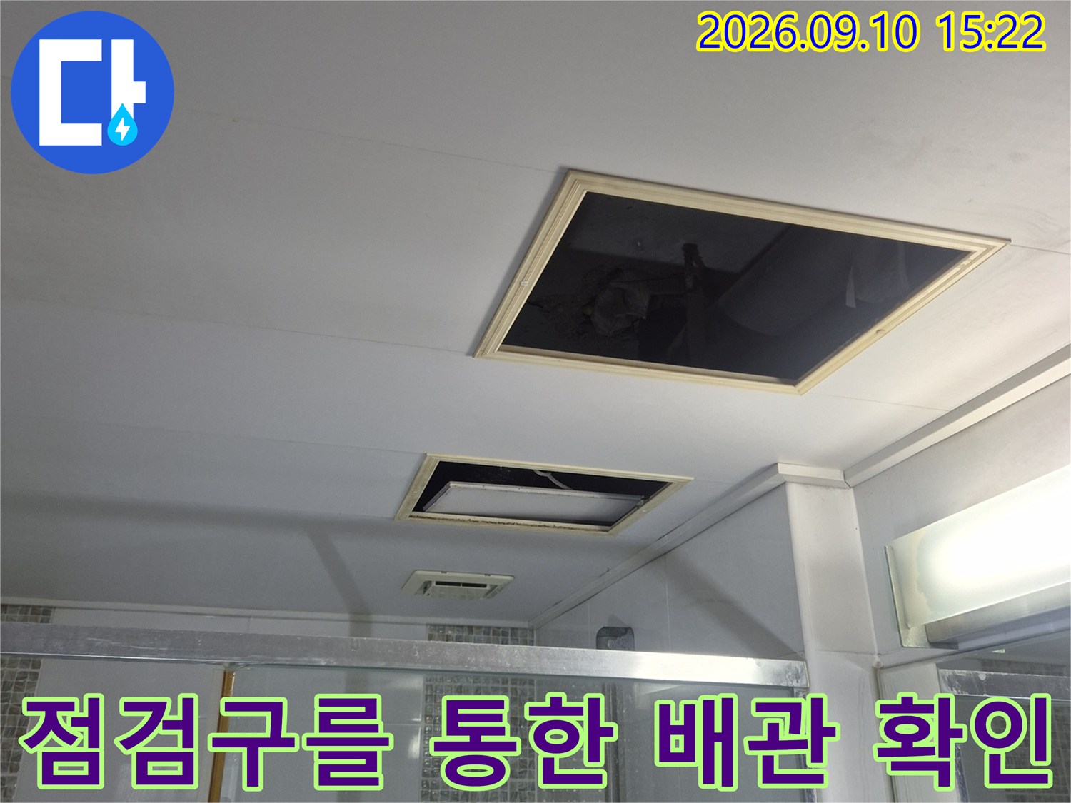 화장실 천장 점검구를 열어 내부 구조와 배관을 관찰하고 있습니다.