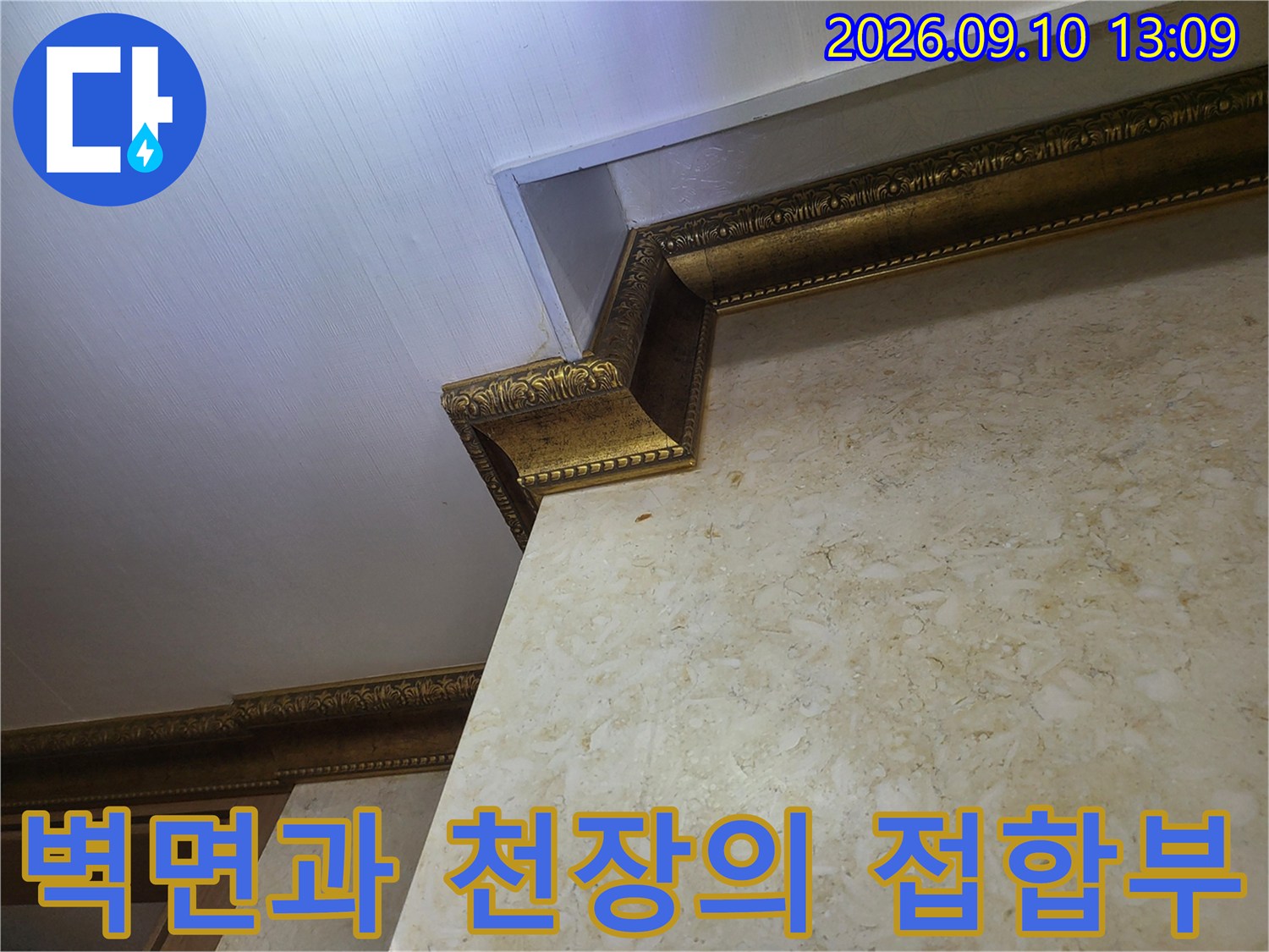 대리석 패턴의 벽면 상단에 위치한 금색 장식 몰딩 상세 사진입니다.