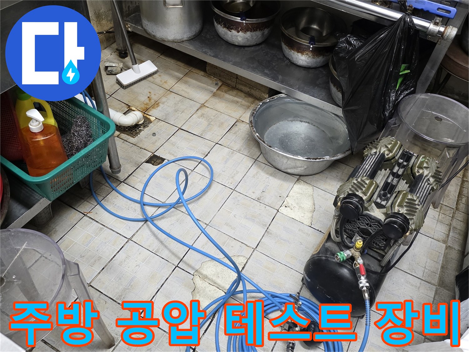 식당 주방 바닥에 설치된 배관 압력 체크를 위한 공압 테스트 장비와 파란색 호스