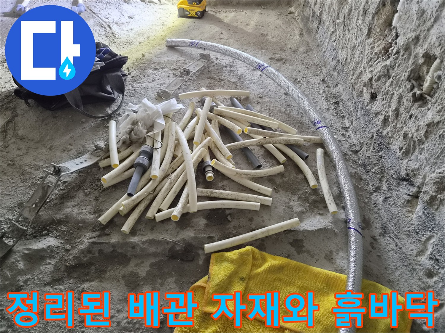 공사 현장 바닥 - 제거된 배관 조각들과 새롭게 연결될 긴 배관의 모습