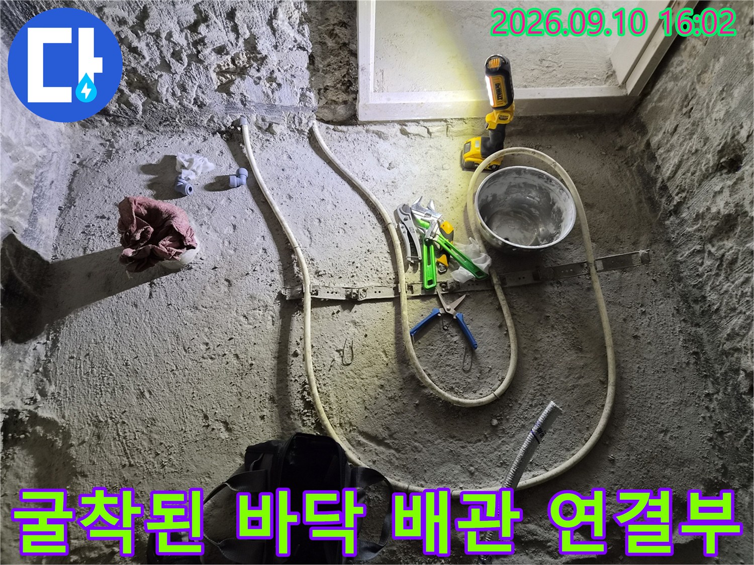 화장실 리모델링 현장에서 노출된 난방 배관과 작업용 공구들입니다.