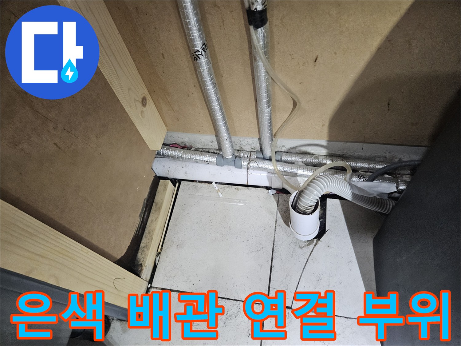 세면대 아래쪽 은색 보온재 배관과 흰색 수전 호스 연결 모습입니다.