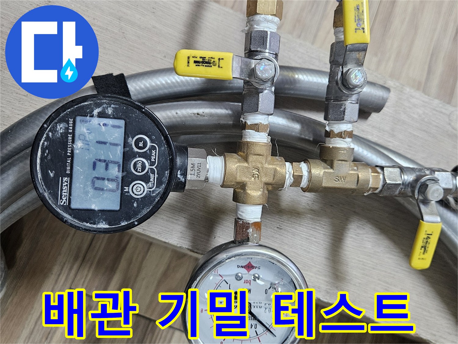 수도 배관 연결 부위에 설치된 디지털 압력계와 아날로그 게이지의 근접 촬영입니다.