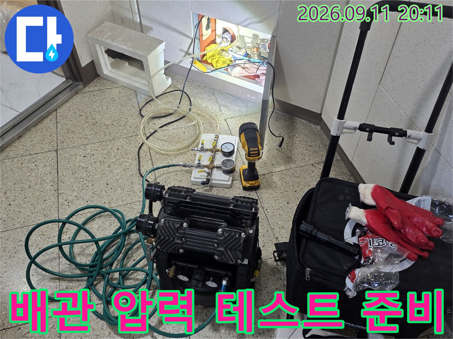 세면대 배관 누수 지점을 찾기 위해 공압 장비와 드릴을 배치한 모습입니다.