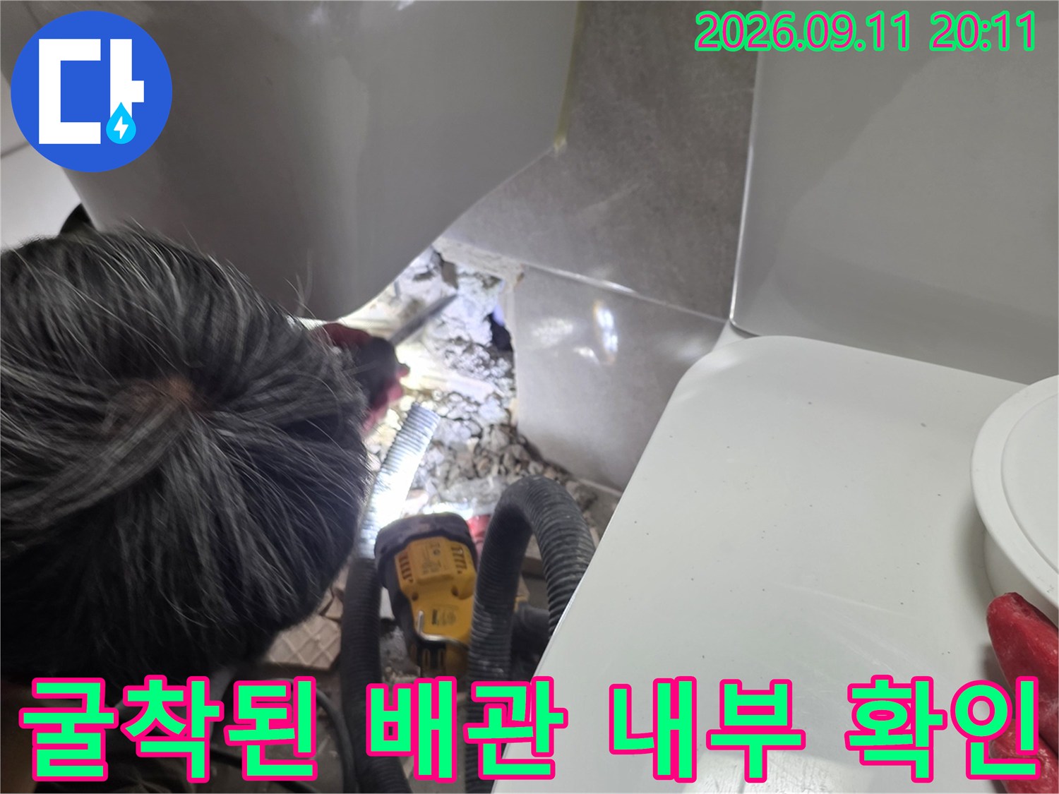 타일을 제거하고 드러난 배관 주변의 젖은 상태를 촬영한 사진입니다.