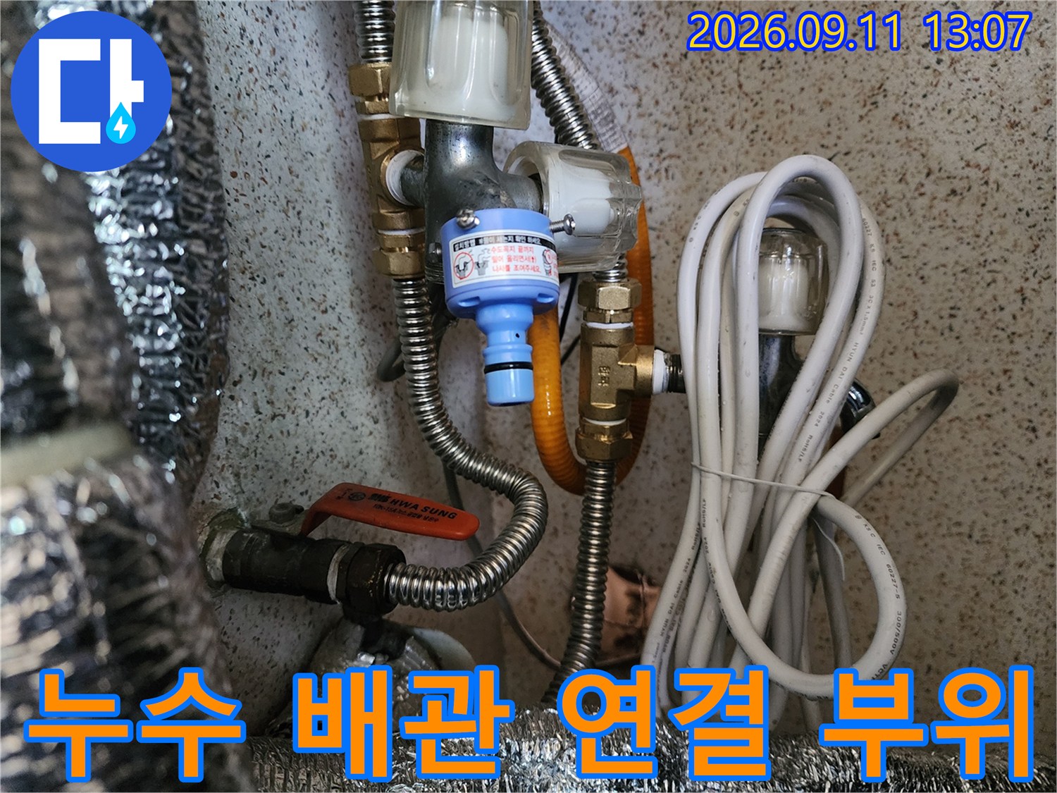 금속 재질의 밸브와 필터가 연결된 온수 배관의 모습입니다.