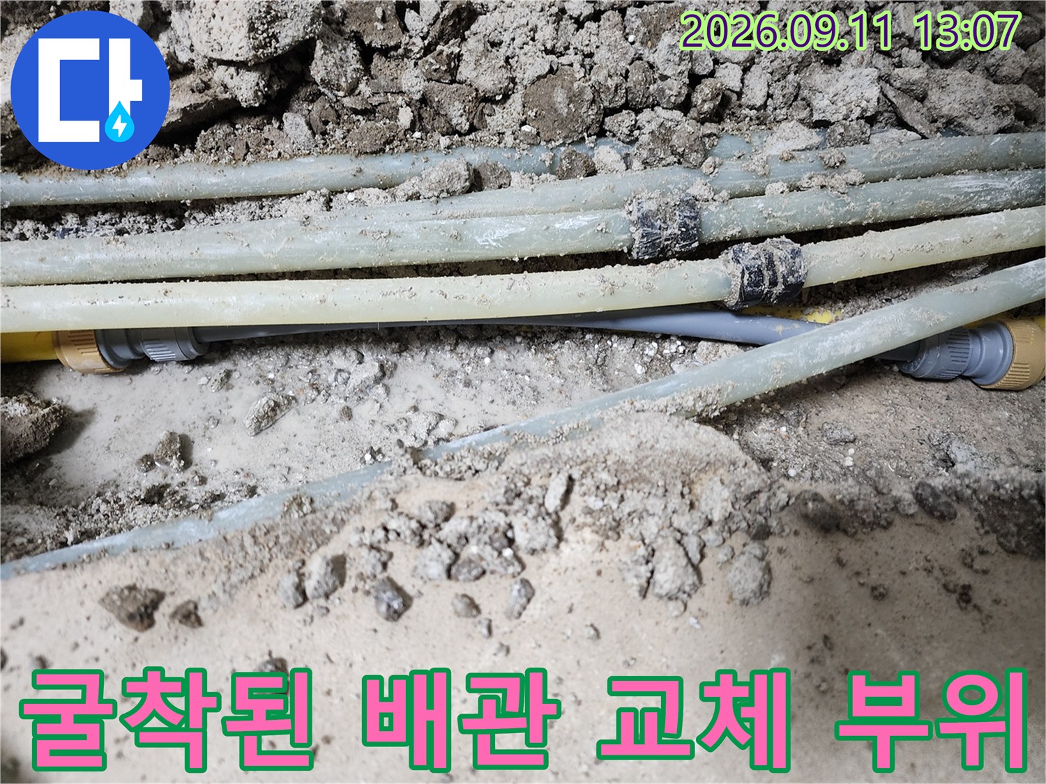 바닥을 굴착하여 노출시킨 온수 배관의 보수 작업 현장입니다.