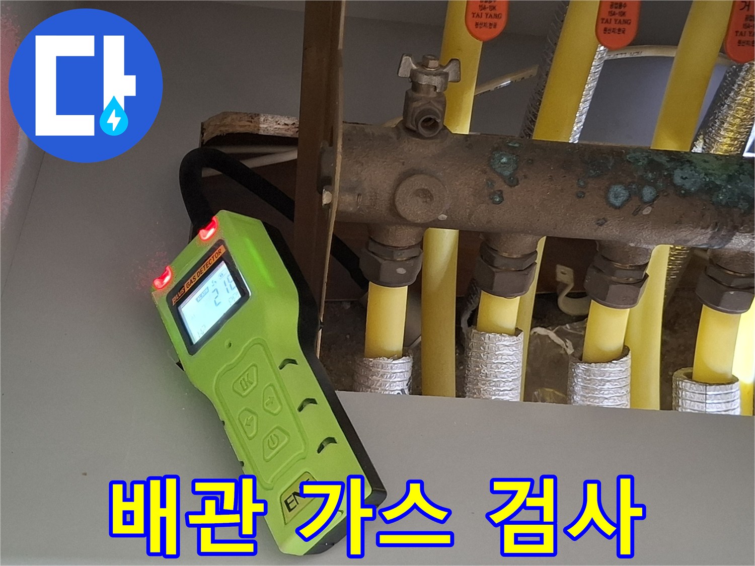 노란색 난방 배관 사이에서 작동 중인 휴대용 가스 탐지기
