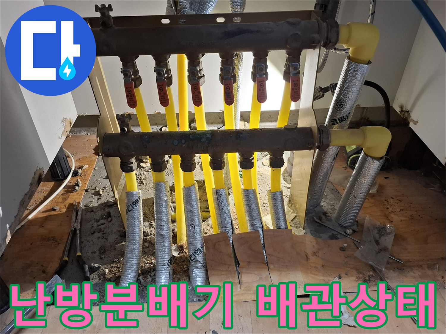 싱크대 하부장 아래 노출된 난방 분배기와 노란색 엑셀 배관의 모습입니다.