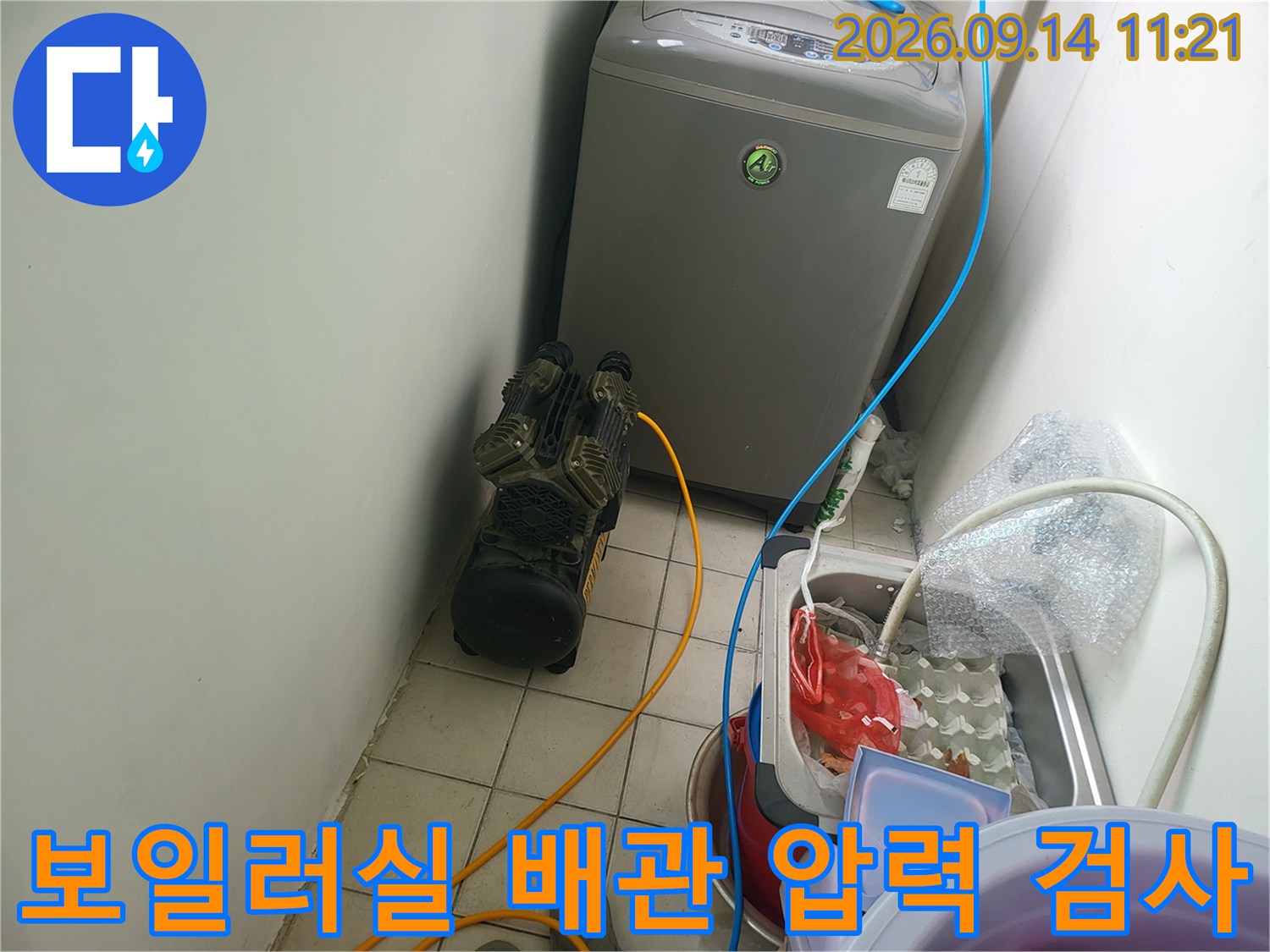 보일러실 바닥에 설치된 공기압 테스트 장비와 연결된 배관 호스 모습