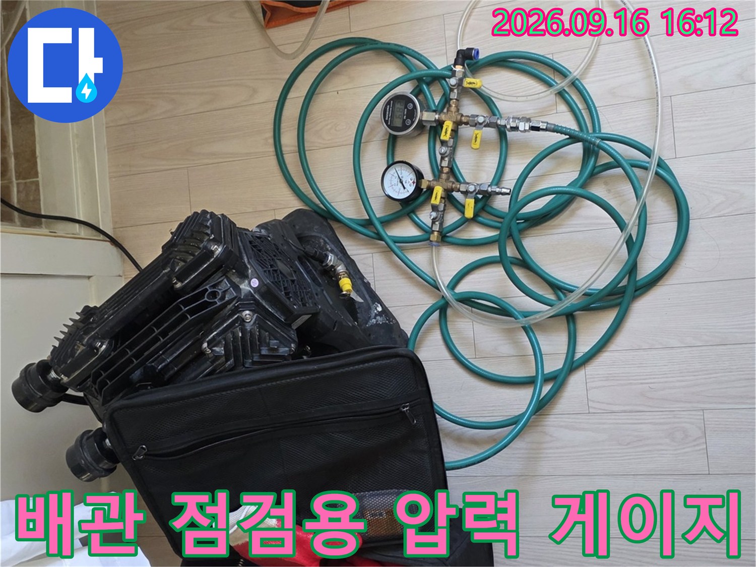 바닥에 놓인 누수 탐지용 디지털 압력계와 푸른색 배관 호스들