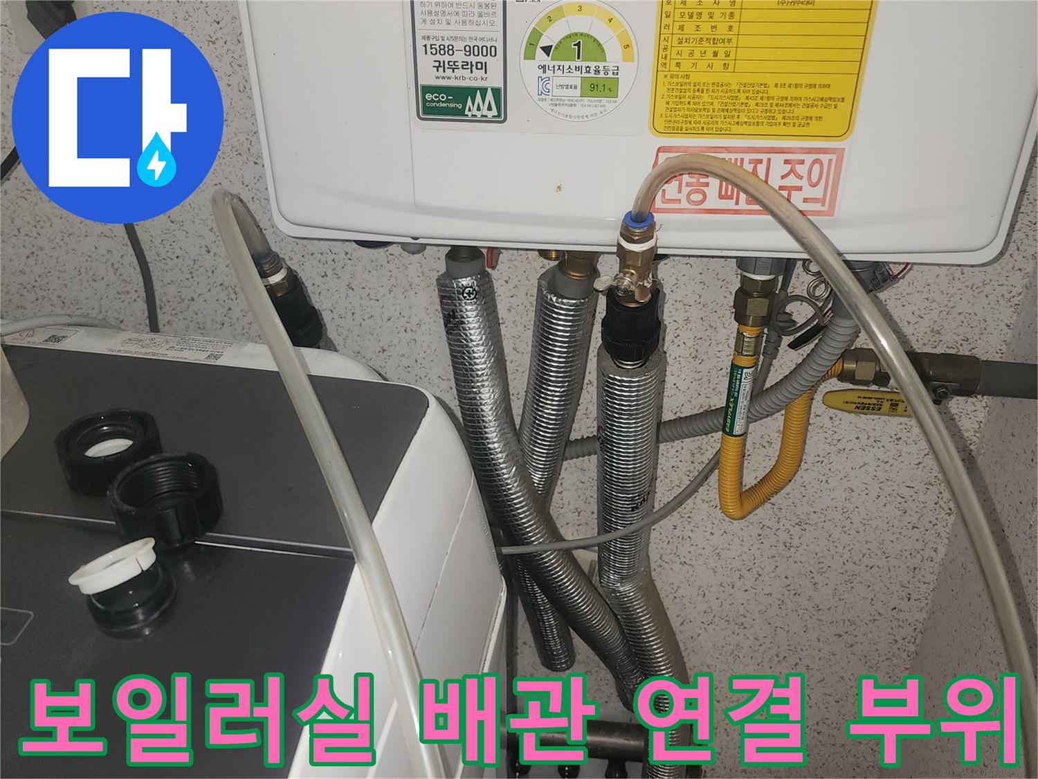보일러 하단에 복잡하게 얽힌 금속 주름관과 급수 라인