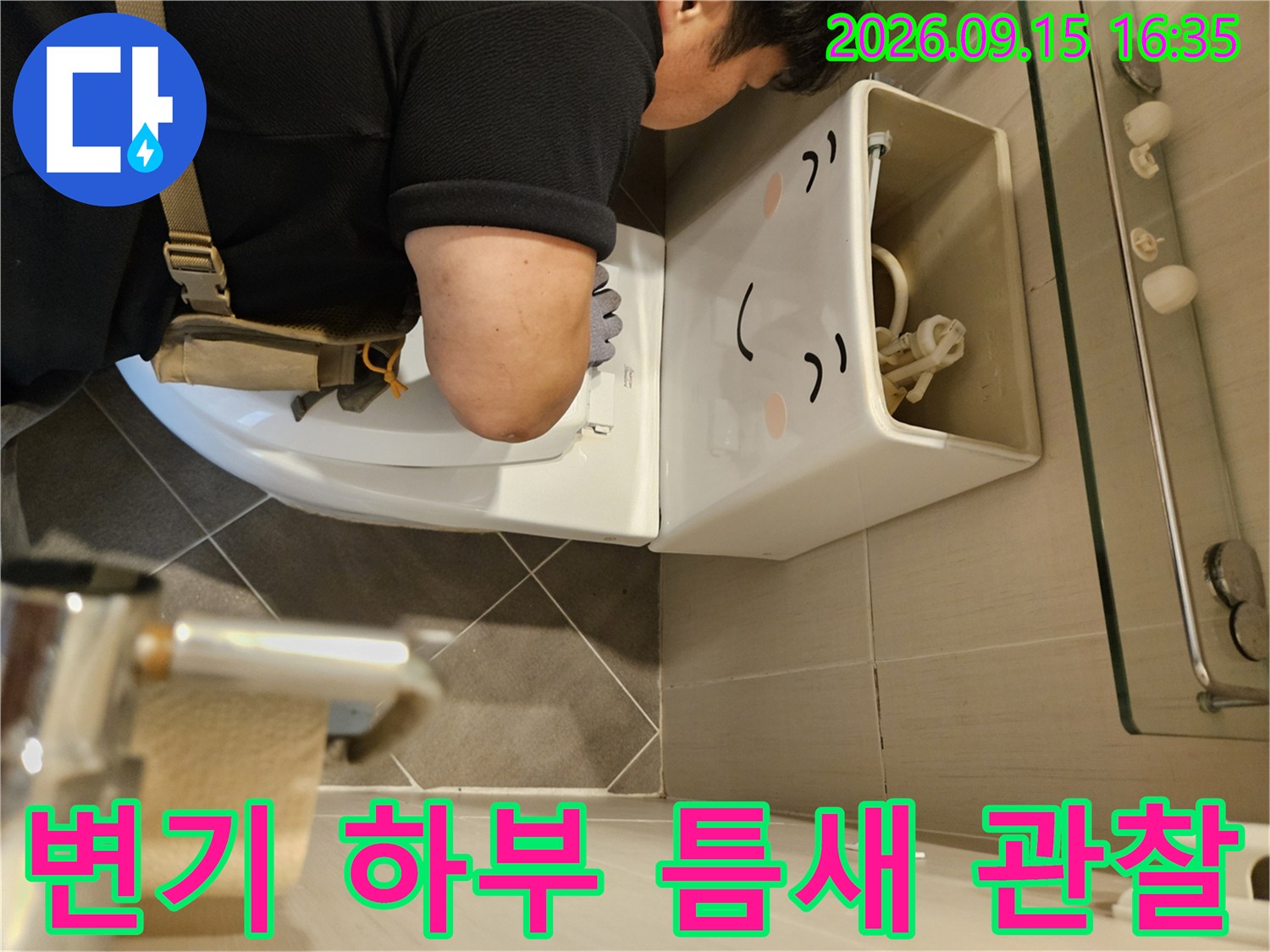 변기 아래쪽 타일 사이의 누수 흔적을 찾아내는 점검 작업 장면